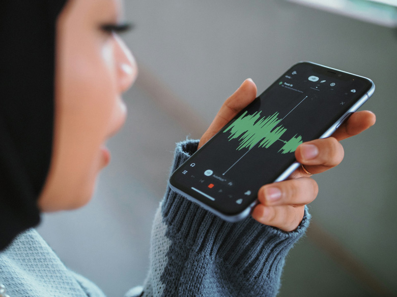 Hand holding a phone while dictating a text message with WhatsApp's microphone open
